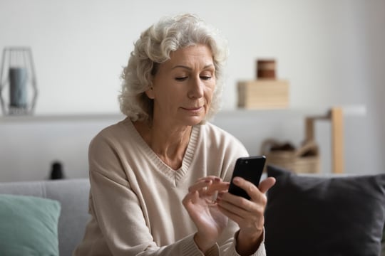 4151_Focused mature woman using phone at home