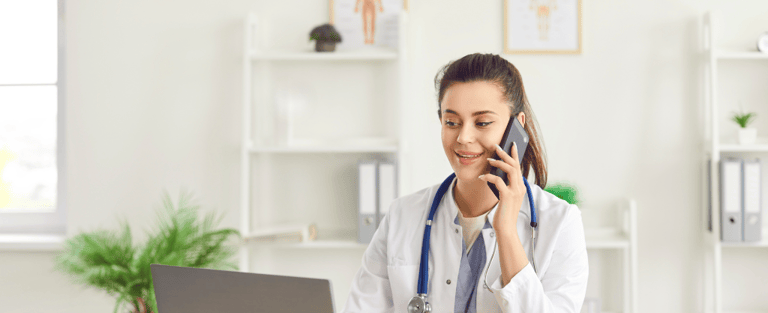 A woman in a white coat is talking on the phone, appearing engaged in conversation